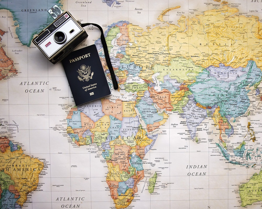 concepto de turismo con pasaporte y camara sobre mapa mundo